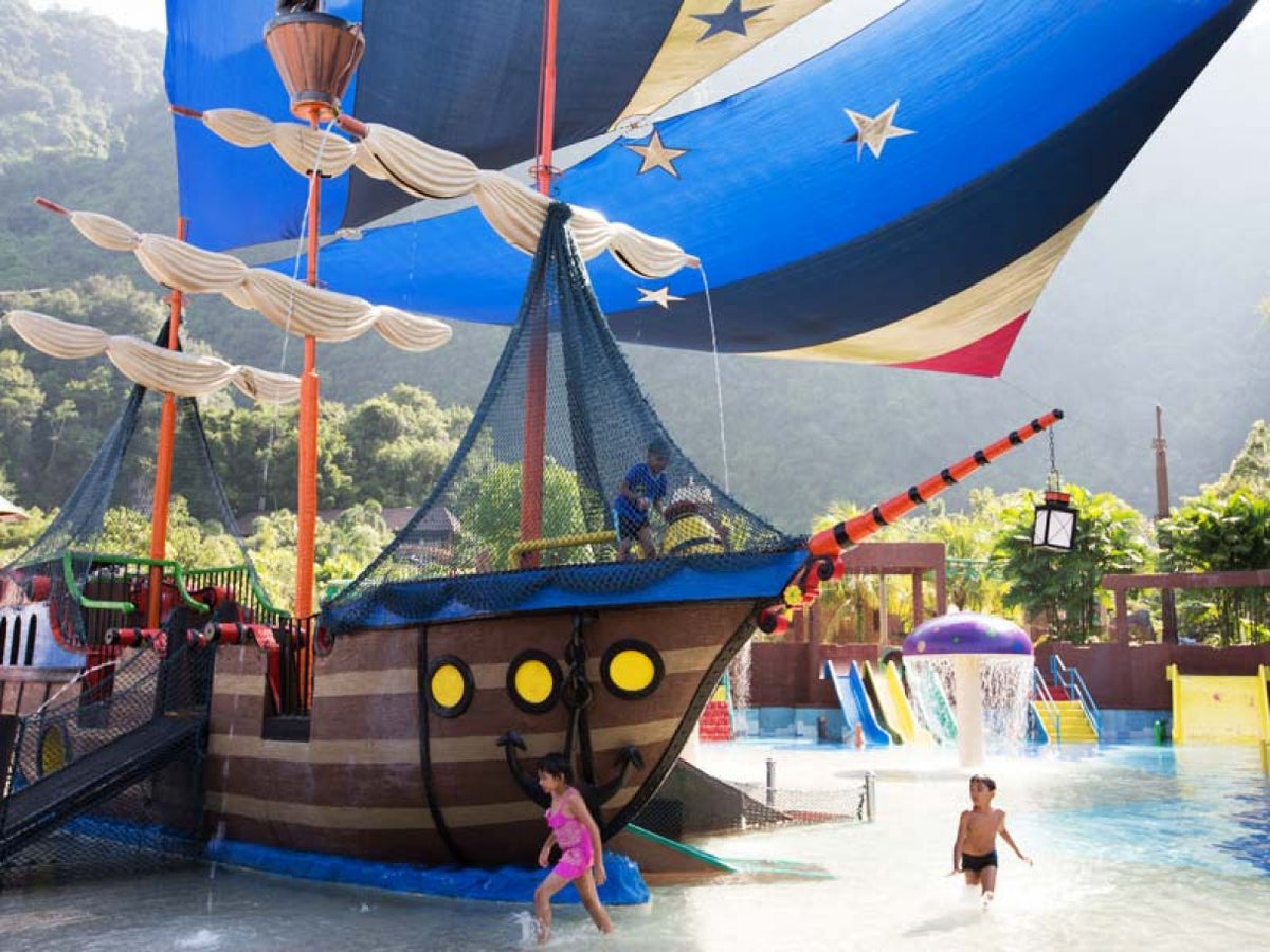 A pirate ship structure in the children's water play area under a striped canopy.