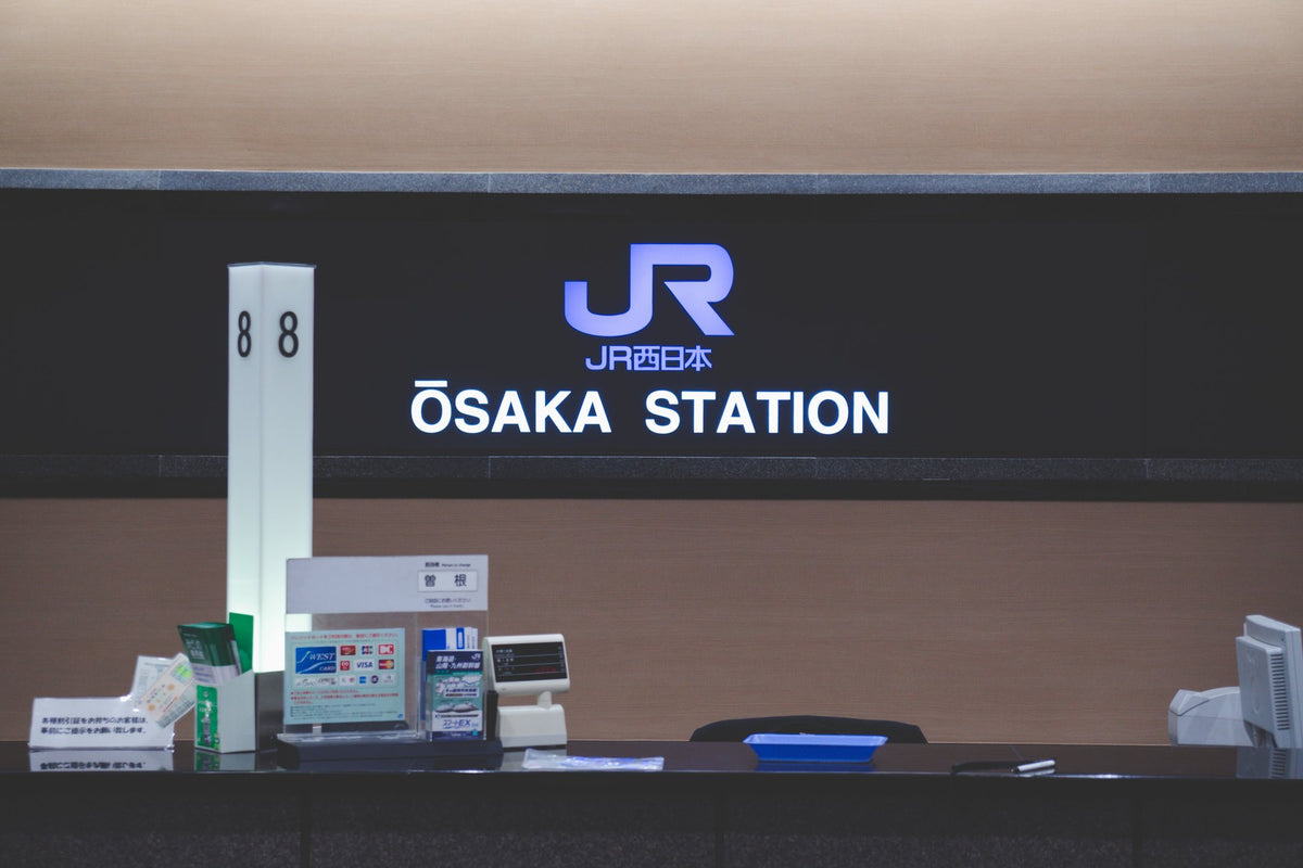 The JR ticket counter at Osaka Station, where a rail pass voucher is exchanged, under the illuminated JR West sign.