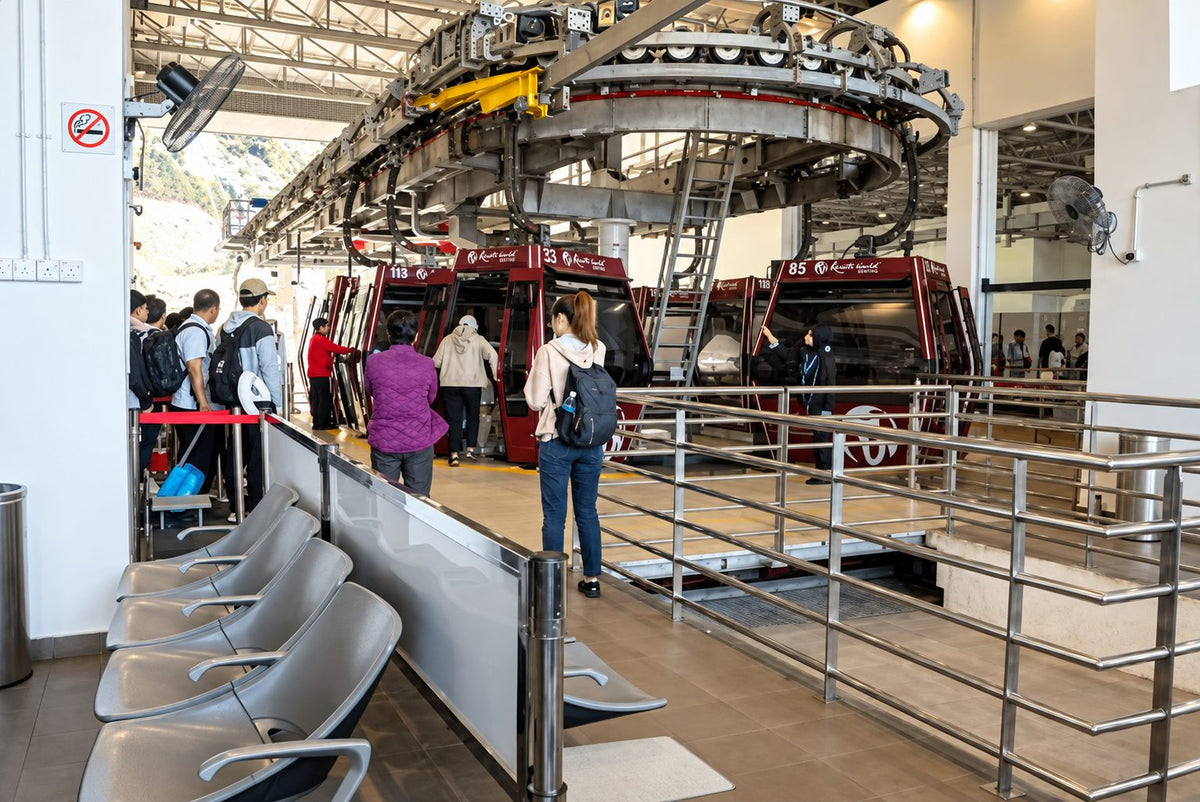 Passengers boarding red Resorts World Genting gondolas inside the cable car station, with staff holding the doors open.